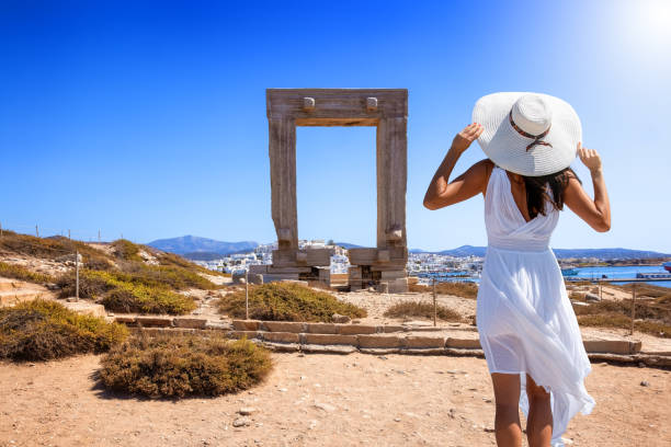 una-mujer-turista-con-un-vestido-blanco-de-verano-mira-la-famosa-puerta-de-mármol-de-la-isla